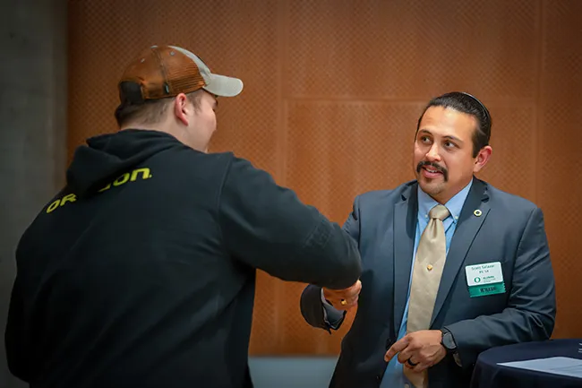 Two alumni shake hands