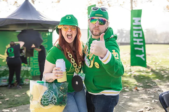 A man and woman pose in Ducks gear at a Mighty Oregon Tailgate