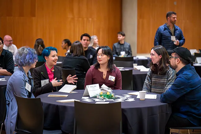 Students and alumni network at a table