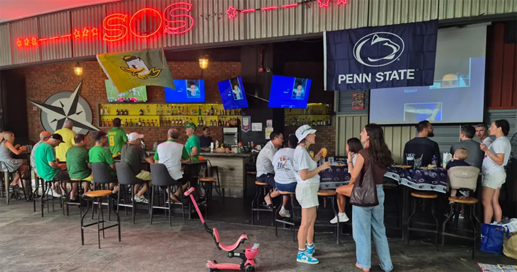 An Oregon Ducks and a Penn State flag hang side by side at a bar.