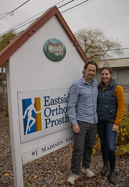 A man and woman stand close together in front of a sign that says Eastside Orthopedics and Prosthetics.