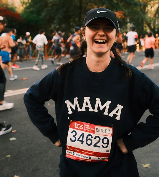 Bailey Holloway laughs at the camera in running gear and a marathon runner number.