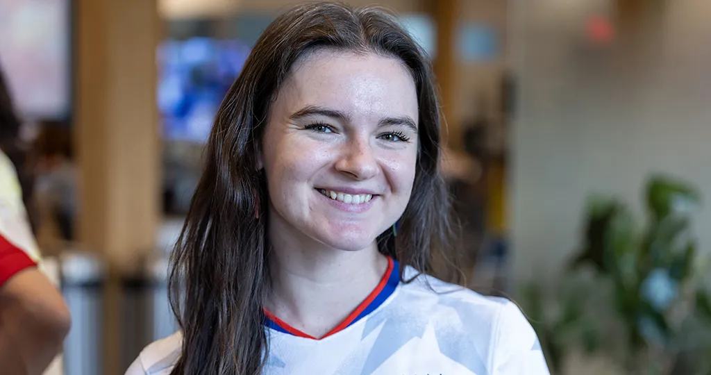 Bailey Holloway, a white woman with long brown hair, smiles at the camera in a Team USA soccer jersey.