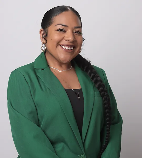 A headshot of Miranda Menard, a Black woman in a green blazer.