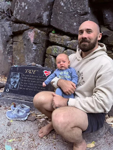 Kevin Flannery holds baby Cal Prefontaine Flannery next to Pre's Rock in Eugene.