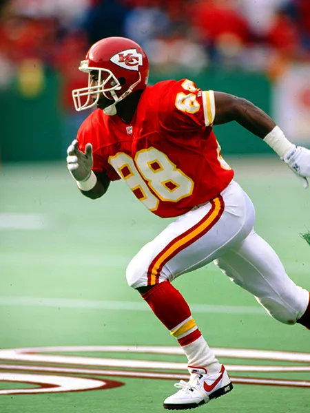 JJ Birden running in a red and white 1990s Kansas City Chiefs uniform.