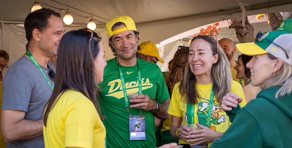 A group of UO alumni talk at an alumni association reunion tailgate