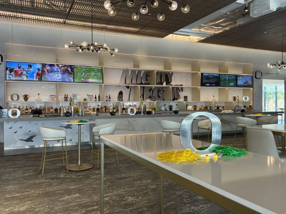 A bar decorated with silver Oregon O stable stands. The back wall is covered in a graphic that says "Mighty Oregon."