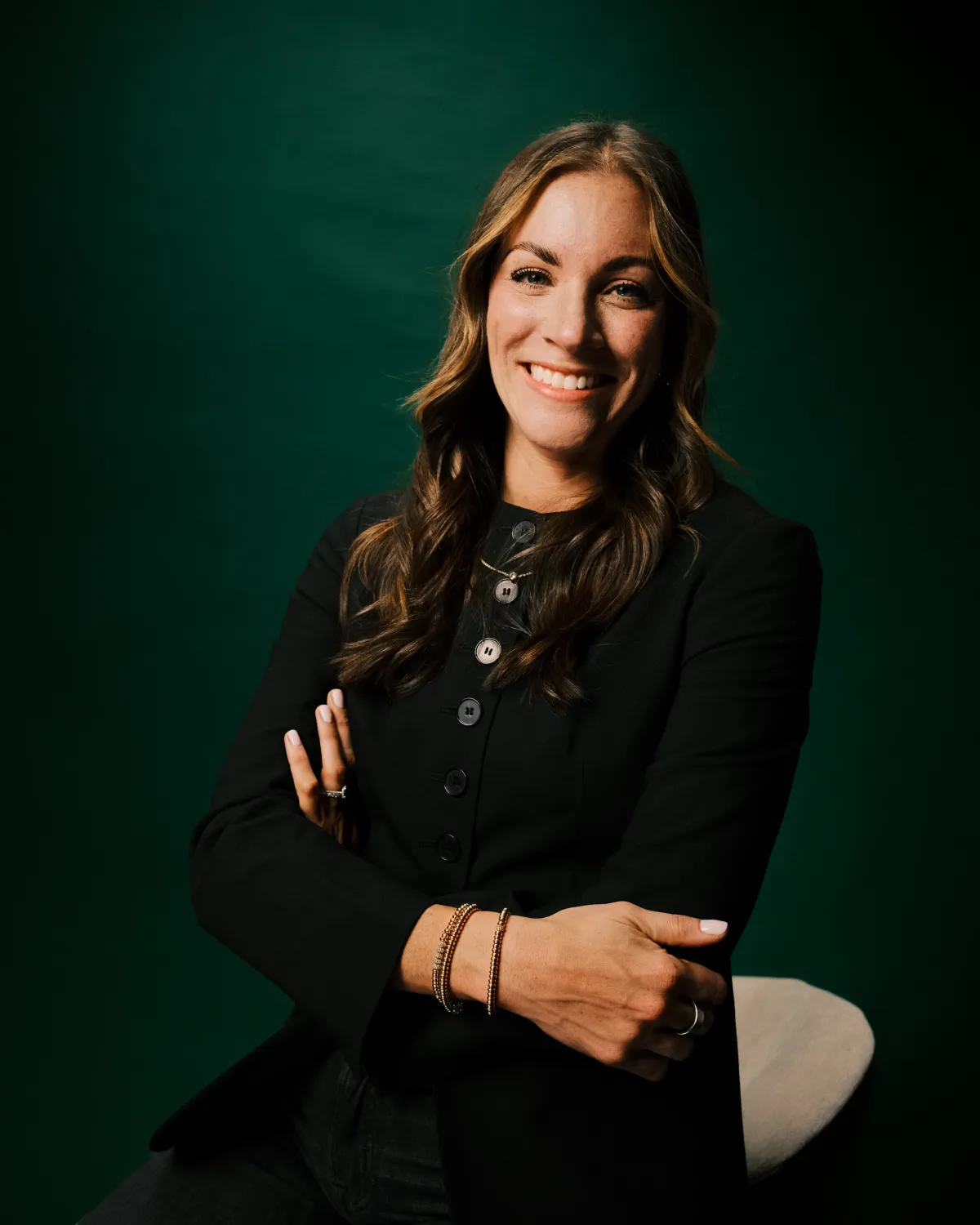 A headshot of Renae Bloom, a woman in a black shirt with long brown hair.