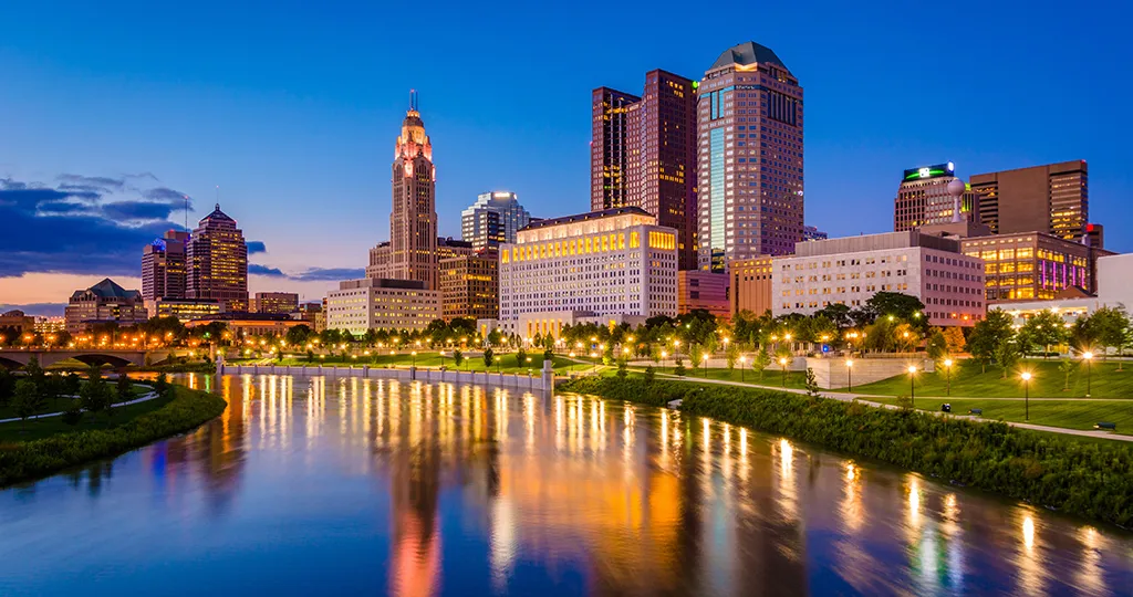 A photo of skyscrapers in Columbus, Ohio on a riverfront during a blue sunset.